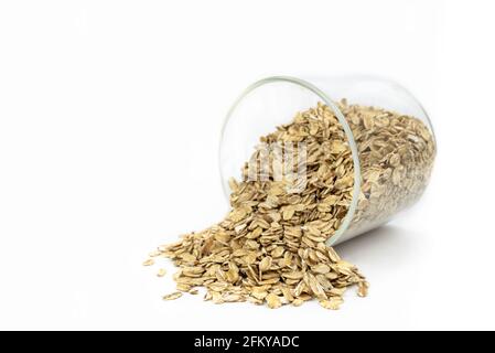 grains d'avoine tombant d'un récipient en verre avec fond blanc Banque D'Images