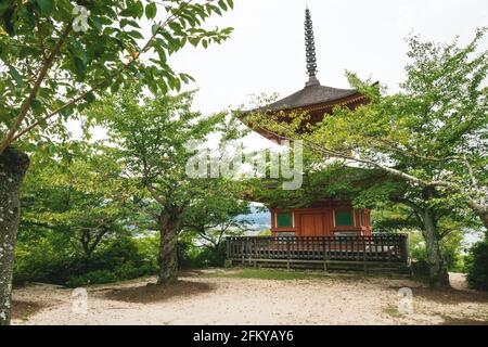 La petite pagode Tahota à deux étages entourée de ginko baignés de soleil sur l'île du sanctuaire Miyajima, Hiroshima, Japon Banque D'Images