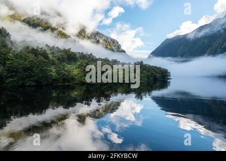 Une nouvelle matinée à la baie de Doutful, des nuages qui pendaient bas dans les montagnes, île du Sud de la Nouvelle-Zélande Banque D'Images