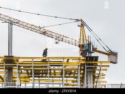 Belarus, Minsk - 07 mars 2020 : une grue industrielle à tour construit un nouveau bâtiment de ville en béton ou des appartements sur le chantier de construction. Banque D'Images