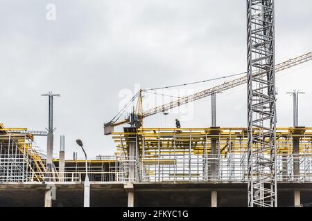 Belarus, Minsk - 07 mars 2020 : une grue industrielle à tour construit un nouveau bâtiment de ville en béton ou des appartements sur le chantier de construction. Banque D'Images