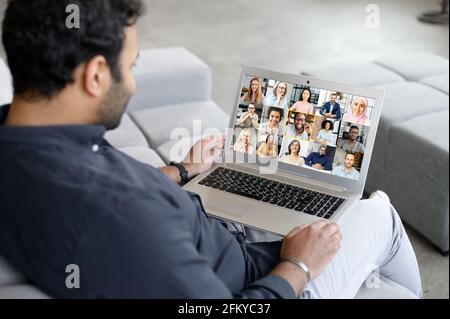 Jeune indien utilisant un ordinateur portable pour des réunions virtuelles avec des collègues, brainstorming avec une équipe multiraciale en ligne, groupe de personnes diverses sur l'écran. Application de communication vidéo, concept d'appel vidéo Banque D'Images