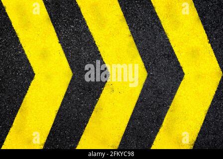 Vue de dessus de la route en asphalte humide sombre avec trois flèches jaunes. Arrière-plan texturé haute résolution plein cadre d'asphalte noir, vu d'en haut. Banque D'Images