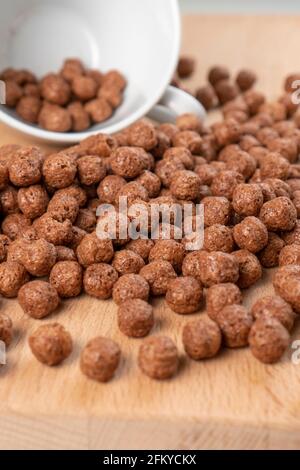 Céréales croquantes au chocolat avec une tasse blanche. Boules de flocons texturés. Macro Banque D'Images