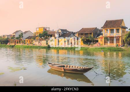 Un seul bateau vietnamien traditionnel sur la rivière Thu bon pendant un coucher de soleil doré dans le village pittoresque de la vieille ville Hoi an, Vietnam. Banque D'Images