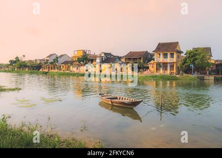 Un seul bateau vietnamien traditionnel sur la rivière Thu bon pendant un coucher de soleil doré dans le village pittoresque de la vieille ville Hoi an, Vietnam. Banque D'Images