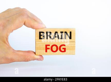 Medical et COVID-19 symbole de brouillard cérébral du coronavirus pandémique. Le médecin tient des blocs de bois avec les mots « brain FOG ». Magnifique fond blanc. Copier l'espace. Banque D'Images