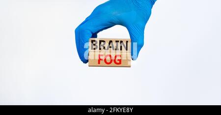 Medical et COVID-19 symbole de brouillard cérébral du coronavirus pandémique. Le médecin tient des blocs de bois avec les mots « brain FOG ». Magnifique fond blanc. Copier l'espace. Banque D'Images