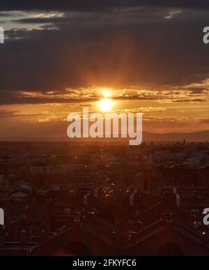 Panoramique de la ville sous la lumière dorée de la coucher du soleil vu d'une élévation dans laquelle les bâtiments et le ciel couvert par un dense cloo noir Banque D'Images