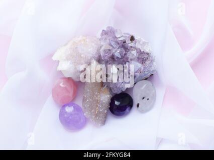 Belles pierres améthystes violettes et cristaux de quartz améthystes sur un tissu blanc transparent. Cactus quartz, connu sous le nom de Spirit quartz. Banque D'Images