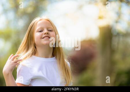 Jolie petite fille de huit ans dehors au soleil souriant Banque D'Images