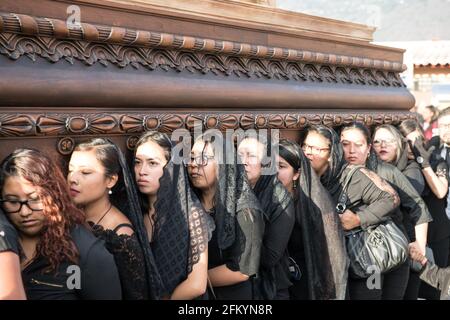 Les femmes portent un flotteur en bois élaboré (anda) lors de la procession Semana Santa à Antigua, Guatemala, une manifestation colorée de foi et de tradition. Banque D'Images