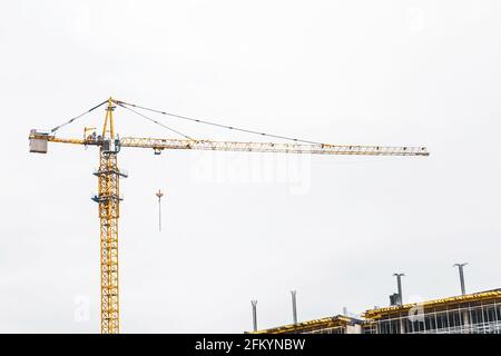 Une grue industrielle à tour construit un nouveau bâtiment de ville en béton ou des appartements sur le chantier de construction. Banque D'Images