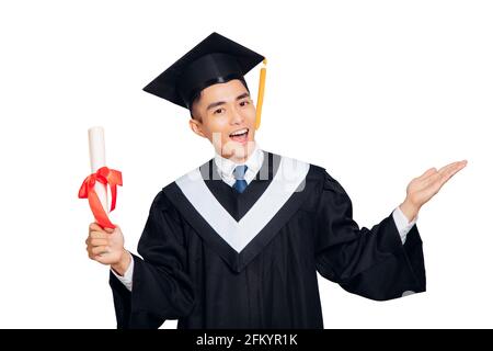 jeune homme en robe de graduation noire et casquette tenant un diplôme isolé sur fond blanc Banque D'Images