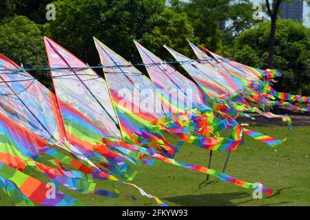Ligne de cerfs-volants colorés en arc-en-ciel à vendre dans un parc, en battant dans le vent lors d'une journée parfaite pour voler. Banque D'Images