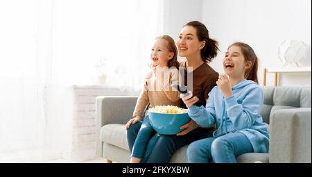 Bonne famille regardant la télévision, films avec pop-corn le soir à la maison. Mère et filles passent du temps ensemble. Banque D'Images