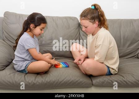 Deux enfants multiraciaux mignons jouant avec le violon Pop IT. Pousser pop bulle flexible violon jouet sensoriel fournir décharge et sont bons pour le développement de l'enfant. Banque D'Images