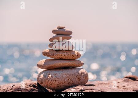 Pierres de pyramide sur le bord de mer lors d'une journée ensoleillée sur le fond bleu de la mer. Joyeuses vacances. Plage de galets, mer calme, destination de voyage. Concept de heureux Banque D'Images