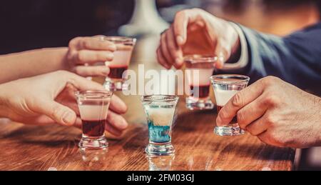 Groupe d'amis tequila shot verres au bar. Mains mâles verres de grenaille ou de liqueur. Les amis boivent une dose ou une liqueur. Cinq verres d'alcool Banque D'Images