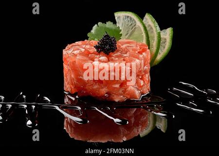 Tartare de saumon avec caviar, lime, sauce soja sur fond noir Banque D'Images