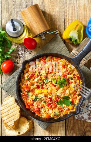 Cuisine turque traditionnelle. Mememen (légumes frits avec œuf brouillés) dans une poêle en fonte sur une table en bois. Vue de dessus de l'arrière-plan de la mise à plat Banque D'Images