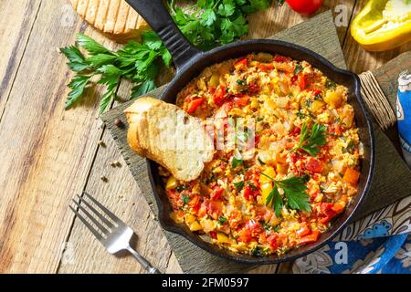 Cuisine turque traditionnelle. Mememen (légumes frits avec œuf brouillés) dans une poêle en fonte sur une table en bois. Vue de dessus de l'arrière-plan de la mise à plat Banque D'Images