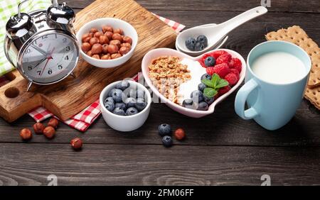 Petit déjeuner sain avec granola maison au yaourt et baies fraîches sur fond de bois. Concept de repas du matin Banque D'Images