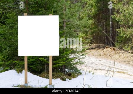 Affiche d'information blanche ou publicité vierge affiche publicitaire espace réservé dans la forêt. Blanc vide panneau d'information dans la forêt de pins d'hiver pour bannière d'information extérieure Banque D'Images