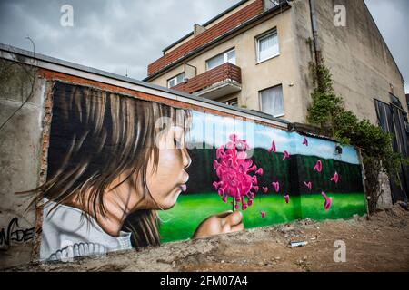 Ein Graffiti an einer alten Mauer zeigt ein Mädchen, welches wie bei einer Pusteblume ein coronavirus anpustet, welches dann auseinander fliegt. Ein s Banque D'Images