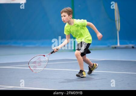 Un garçon avec une raquette de tennis sur le court joue au tennis. Banque D'Images