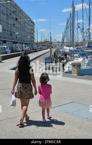 Femme ou fille philippine asiatique marchant main dans la main avec sa fille mixte sur le port de Carnon Plage près de Montpellier, Occitanie, sud de la France Banque D'Images