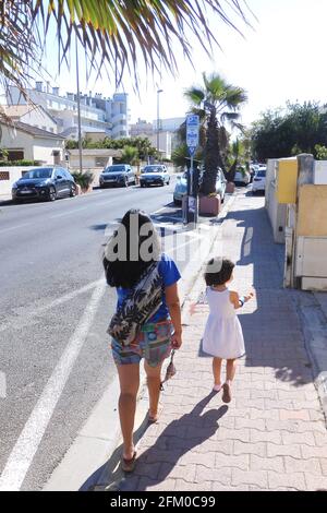 Femme ou fille philippine asiatique vêtue d'une robe noire suite à sa fille mixte à Palavas les Flots près de Montpellier, Occitanie, sud de la France Banque D'Images