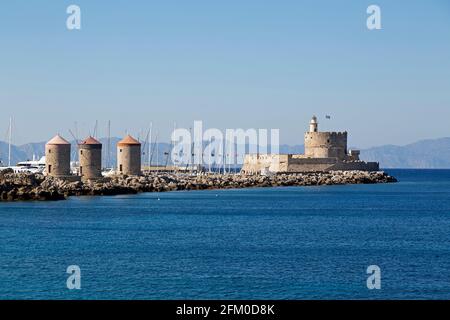 Le fort de Saint Nicolas dans la ville de Rhodes en Grèce. La forteresse du XVe siècle iis sur un mur de port avec les trois moulins en pierre de Mandraki. Banque D'Images