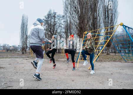 Cours de fitness en groupe à l'extérieur. Cours d'entraînement en plein air socialement distants dans les parcs publics. Trois femmes et l'homme s'entraîner ensemble dans le public Banque D'Images