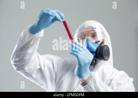 Un homme en costume médical de protection tient un tube à essai dans ses mains. Le concept de vaccins ouverts contre le coronavirus Banque D'Images