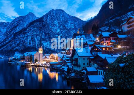 Hallstatt CityScape lors d'une soirée d'hiver froide couverte de neige Avec le lac Hallstaetter Voir et l'église illuminée la nuit Banque D'Images