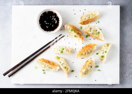 Giaozi, Gyoza, boulettes chinoises servies avec une sauce soja sur un plateau de marbre blanc. Vue de dessus Banque D'Images