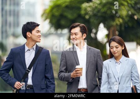 trois hommes d'affaires asiatiques qui marchent dans la rue Banque D'Images