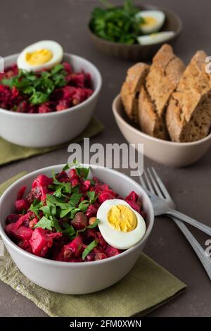 Salade russe vinaigrette dans des assiettes avec oeuf bouilli, salade de pommes de terre bouillies et carottes, betteraves et légumes marinés, concombre et chou Banque D'Images