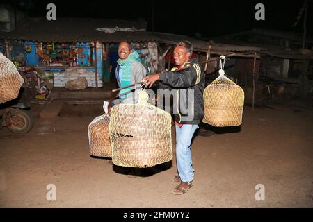 Konda Doras et Nooka Doras hommes tribaux transportant des grains dans de grands paniers de bambou dans le marché de nuit d'Araku Village, Andhra Pradesh, Inde Banque D'Images