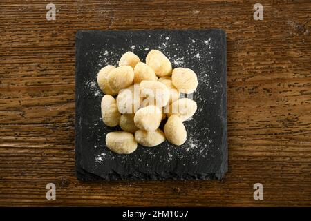 Vue de dessus des pâtes italiennes gnocchi non cuites placées à bord sur la table de bois Banque D'Images