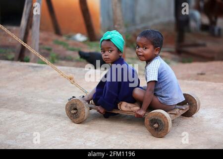 Bhakta tribal petits enfants assis sur une charrette à jouets en bois à Hattaguda Village, Andhra Pradesh, Inde Banque D'Images