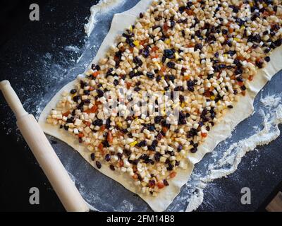 Procédé de fabrication de strudel de pomme, une couche de pâte avec la garniture sur la table, le strudel est prêt à être tordus et envoyé au four. Banque D'Images