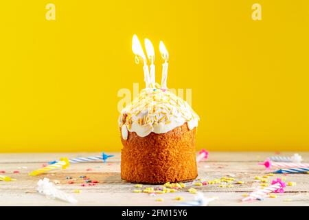 Gâteau de fête avec bougies sur fond jaune. Décorations pour un anniversaire ou des vacances. Banque D'Images