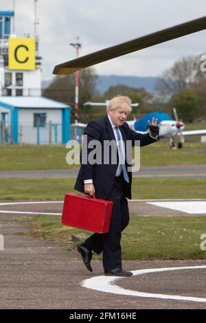 Aéroport de Wolverhampton Halfpenny Green, Royaume-Uni, 5 mai 2021. Le Premier ministre Boris Johnson se fait une vague devant les pillards alors qu'il monte à bord de son hélicoptère après une visite dans le pays noir, le dernier jour de campagne en vue des élections locales du jeudi en Angleterre. Le premier ministre est revenu de Stourbridge où il s'était joint plus tôt au maire de West Midlands, Andy Street, pour une promenade en vélo sur le canal et a aidé à distribuer des dépliants de campagne. Credit: Paul Bunch / Alamy Live News. Banque D'Images