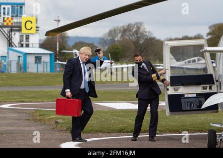 Aéroport de Wolverhampton Halfpenny Green, Royaume-Uni, 5 mai 2021. Le Premier ministre Boris Johnson se fait une vague devant les pillards alors qu'il monte à bord de son hélicoptère après une visite dans le pays noir, le dernier jour de campagne en vue des élections locales du jeudi en Angleterre. Le premier ministre est revenu de Stourbridge où il s'était joint plus tôt au maire de West Midlands, Andy Street, pour une promenade en vélo sur le canal et a aidé à distribuer des dépliants de campagne. Credit: Paul Bunch / Alamy Live News. Banque D'Images