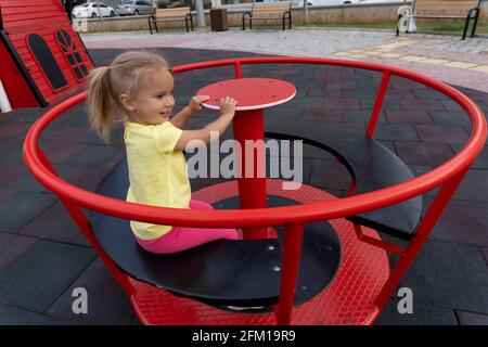 Mignon petit enfant caucasien sur la balançoire à l'aire de jeux Banque D'Images