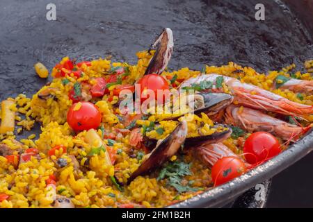 Gros plan : paella cuite aux crevettes, musse, riz, tomates cerises - cuisine de rue Banque D'Images