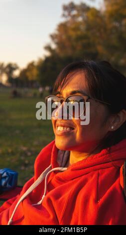 portrait d'une jeune femme portant des lunettes de soleil dans un parc vert le coucher du soleil et le sourire Banque D'Images