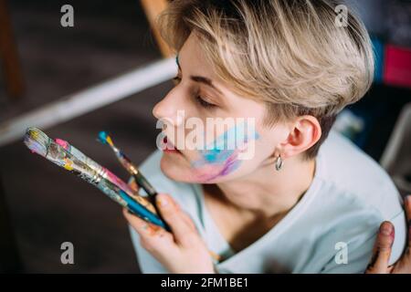 Portrait créatif de la belle jeune femme artiste en studio avec des pinceaux. Banque D'Images